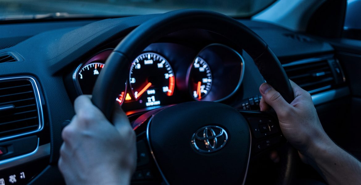 Vue nocturne réaliste du tableau de bord d’une voiture, avec le voyant moteur allumé et des détails des jauges éclairés dans une ambiance informative.