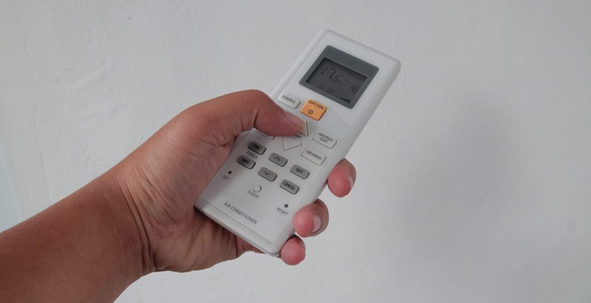 Personne réglant la température d’une climatisation avec sa télécommande
