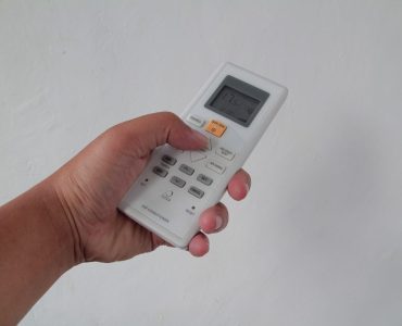 Personne réglant la température d’une climatisation avec sa télécommande
